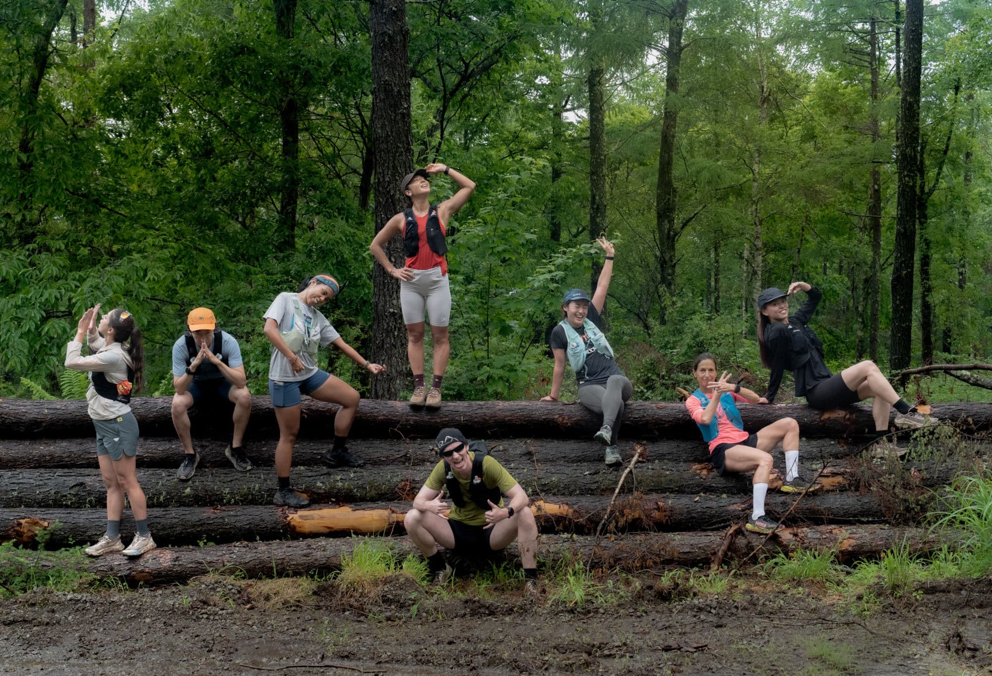 Runners posing along a fallen log in the forest